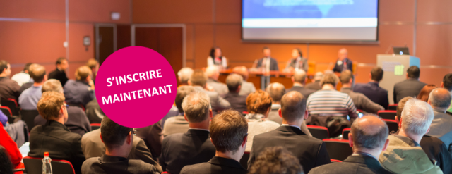 Salle de conférence pleine avec quatre personnes sur la scène qui discutent ensemble